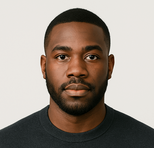 A man with short black hair and a trimmed beard wearing a dark crew-neck sweater looks directly at the camera against a plain light background.